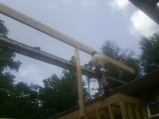 Carpenter setting a ridge beam over a new addition frame — Ice Dam Removal by Roofing Brothers in Turney