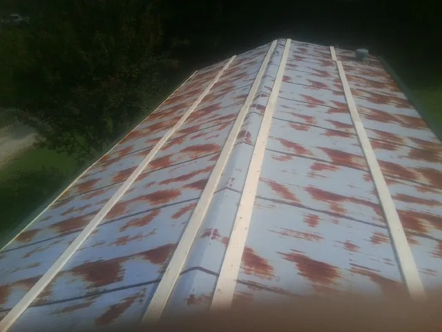 Rusted metal roof panels with new wood purlins before replacement — Storm Damage Roof Repair in Turney by Roofing Brothers