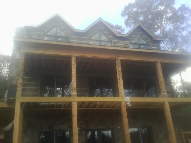 Dormers and porch framing on a large log home under construction — Roof Coating work by our crew in Turney
