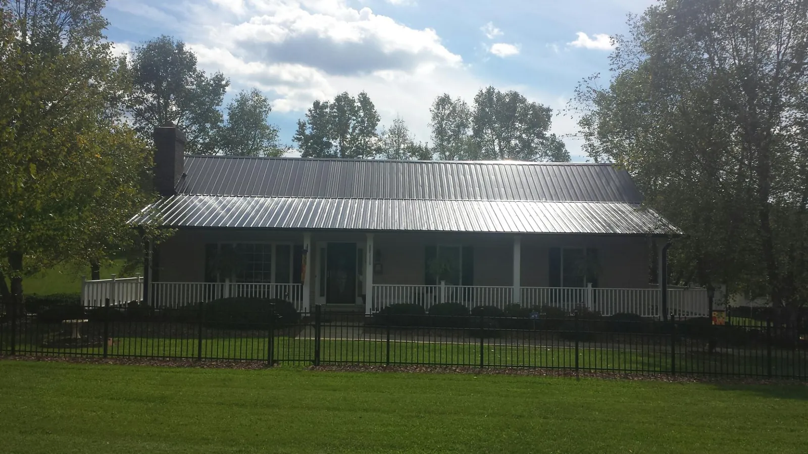 Gray metal roof on a brick ranch with a full width front porch — Gutter Guard Installation work by our crew in Turney
