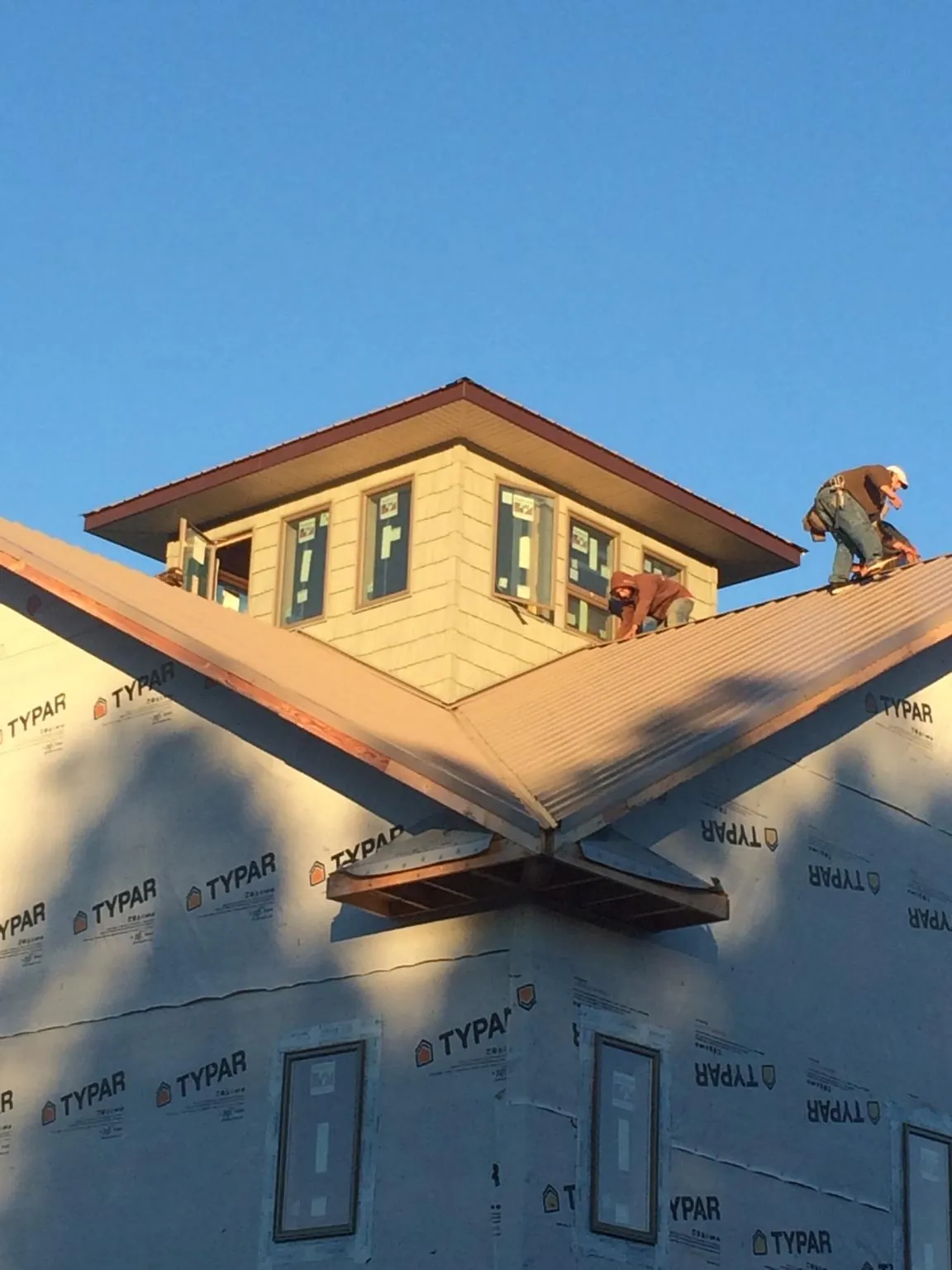 Roofers working around a rooftop cupola on a new metal roof at sunset — Roof Waterproofing in Turney by Roofing Brothers